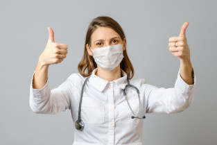 Satisfied young female doctor showing thumb up gesture
